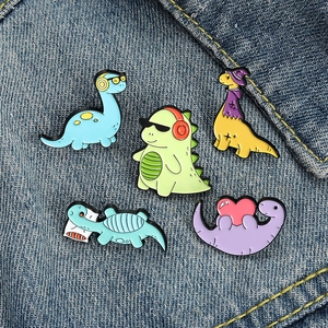 Set of 5 colorful enamel dinosaur pins including musical and cool themes on denim background