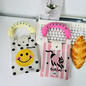 Detail of knitted mini bags featuring smiling face and cartoon cat with plush handles
