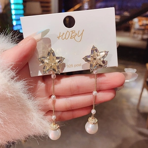 Détail de boucles d'oreilles en argent 925 avec étoiles, pompons de perles et cristaux de zircon