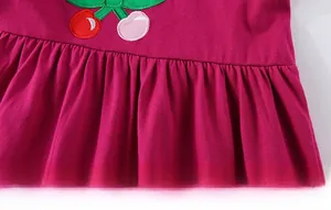 Detailed close-up of cherry embroidery and pleated hem on girls rose pink cotton dress