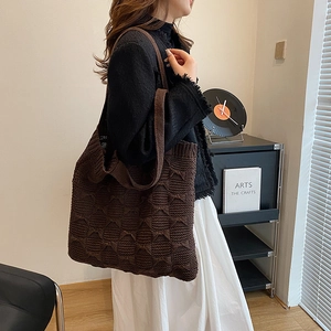 Detailed texture of dark brown knit tote bag shown on a model in a cozy indoor setting