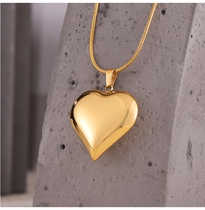 Polished 18k gold heart pendant necklace on minimalist stone stand with sleek snake chain
