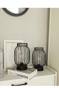 Detail view of black iron lantern lamps with warm LED bulbs on a Nordic white cabinet