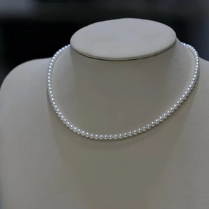 Elegant natural freshwater pearl necklace on display mannequin featuring white round pearls