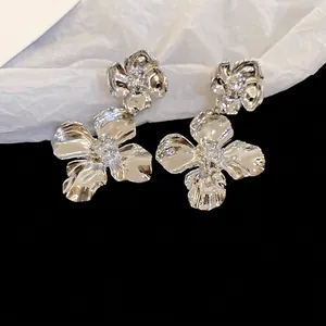 Silver flower drop earrings with irregular petal texture and sparkling zircon centers