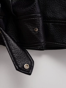 Détail de la texture cuir noir grainé sur la veste avec boutons-pression argentés