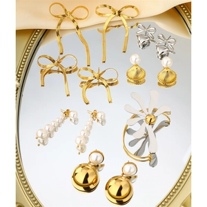 Close-up of golden bow earrings and pearl jewelry displayed on a mirrored gold tray