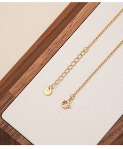 Detail of S925 sterling silver gold clasp and extension chain on wooden tray
