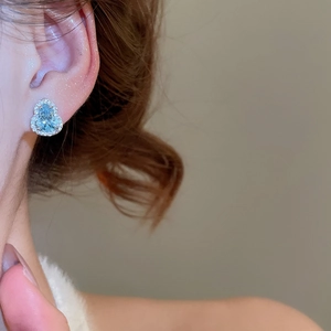 Vue macro de boucles d'oreilles gourde en zircon bleu clair portées par un mannequin