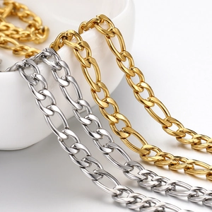Polished gold and silver stainless steel Figaro chains hanging over a white bowl