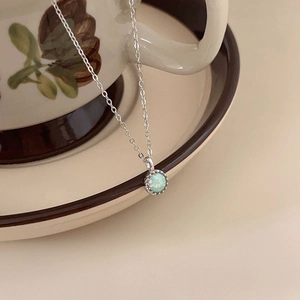 S925 sterling silver necklace with blue round opal pendant draped on ceramic cup