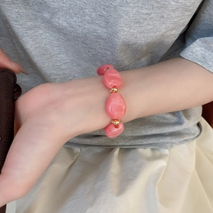 Close-up of irregular pink marble acrylic beads and golden metal spacers on a wrist