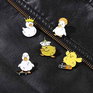 Detail view of five cute cartoon duck and chick enamel pins on black leather background
