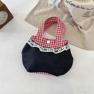 Dettaglio della borsa in denim blu con finiture a quadretti rossi e pizzo bianco