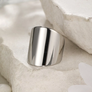 Close-up of wide polished stainless steel ring on a textured white stone base