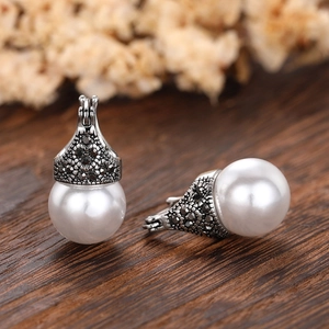 Nahaufnahme von Vintage-Ohrringen im Thai-Silber-Stil mit weißen Perlen und schwarzen Steinen
