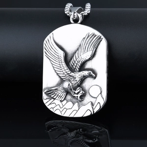 Detailed relief of an eagle soaring over mountains on a silver stainless steel pendant