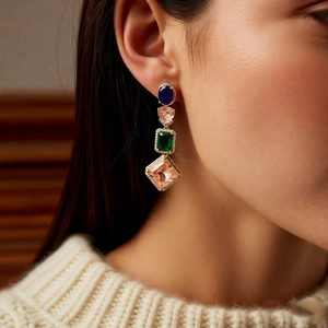 Detailed view of geometric multi-color gemstone drop earrings with gold-tone setting on a model