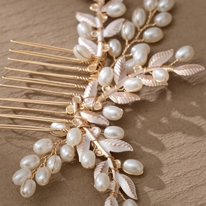 Elegante peineta dorada de novia con perlas y hojas sobre una tela con textura