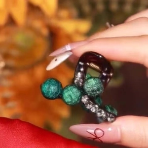 Detail view of a small green bead hair claw clip with rhinestones and resin finish