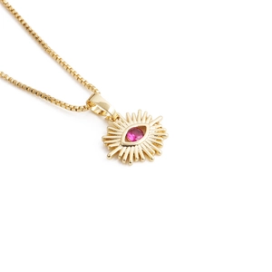 Golden chain necklace with sunburst eye pendant and a pink gemstone on white background