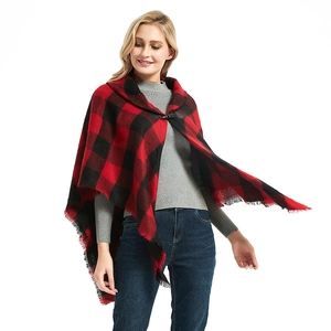 Red and black plaid poncho cape with metal buckles and fringe trim on a white studio background