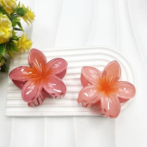 Detailed view of two pink translucent flower hair claws on a white textured base