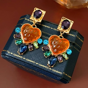 Gros plan de boucles d'oreilles cœur vintage dorées avec cristaux colorés en gouttes