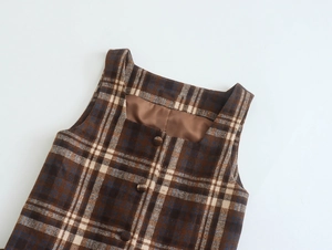 Detail of a brown plaid sleeveless dress featuring a square neck and matching buttons