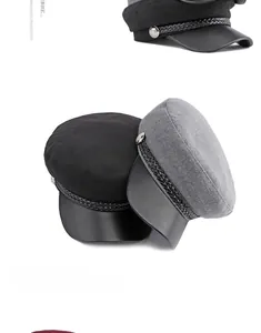 Detail of wool baker boy caps in black and grey with leather brim and metal buttons