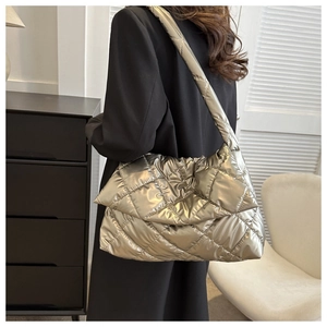 Chic gold quilted crossbody bag with metallic finish shown on model in modern room