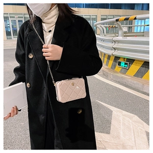 Close-up of beige quilted PVC jelly bag with gold chain strap on a model in city