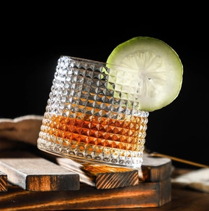Macro detail of diamond pattern glass whiskey tumbler with amber liquid and lime slice