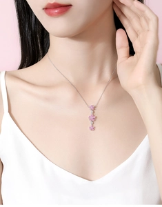 Detail of pink plum blossom necklace on neck with sparkling diamonds and silver chain