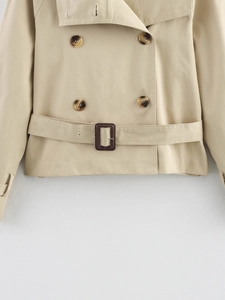 Detail of khaki short trench coat featuring double-breasted buttons and adjustable waist belt