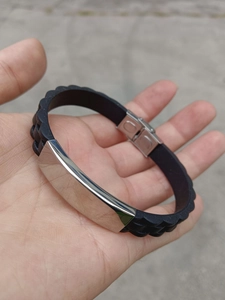Detail of black silicone wristband with textured strap and silver metal ID plate