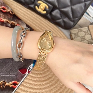 Detailed view of a gold snake-shaped watch with Roman numerals and a scale-textured band