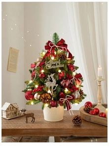 Detail of a mini tabletop Christmas tree with warm LED lights and red gold festive ornaments