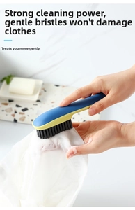 Close-up of blue and yellow long-handled cleaning brush scrubbing white fabric with foam