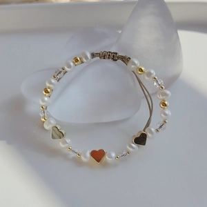 Macro detail of natural freshwater pearl bracelet with red enamel heart and adjustable cord