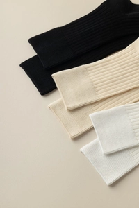 Détail de la texture en maille côtelée sur chaussettes en coton noir, beige et blanc