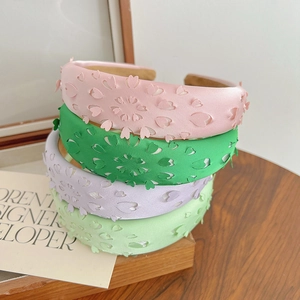 Detail showing stacked floral fabric headbands in pink, green, and purple pastel colors