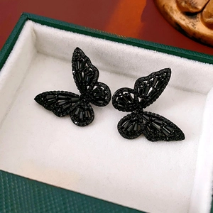 Detailed close-up of black hollow butterfly earrings with sparkling crystals in a gift box