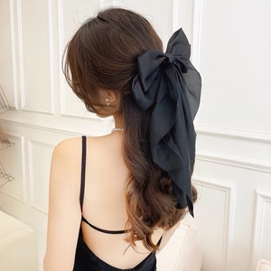 Detail of a large black layered organza bow hairclip with long flowing ribbons on hair
