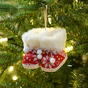 Red and white knitted Christmas boot ornament hanging on tree with soft warm lighting