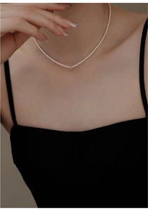 Close-up of minimalist freshwater pearl choker necklace with a tiny 14K gold bead on model