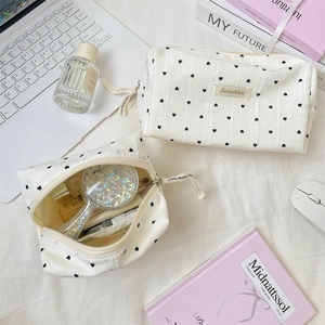 Detail of white jacquard striped makeup bags with black hearts and large interior space