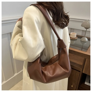 Detail showing the brown lychee-grain leather texture on a retro shoulder bag worn by model