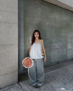 Outdoor street style view of white sleeveless tank top paired with wide-leg jeans and a bag