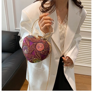 Detail of heart-shaped sequin evening bag with purple floral patterns and gold handle